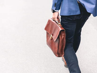 Russell-Cooke employment litigation charging information. Man walking and carrying a brown leather work bag.