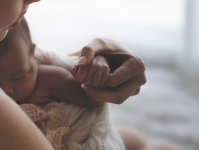 A new born baby holding onto their mothers finger. Russell-Cooke, birth injury solicitors
