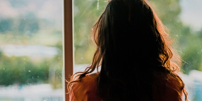 A lady looking out onto greenery through a window. Lost people—has anyone seen my beneficiary?
