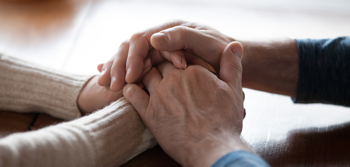 A couple holding hands rested on a table. Fatal accident claims and inquests solicitors