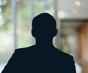 Russell-Cooke Solicitors staff photograph. Silhouette of a female team member against the backdrop of an office window and corridor with a soft focus effect.
