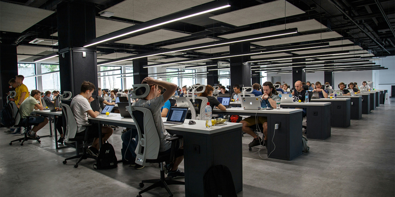 A large office with rows of office workers at computers. 