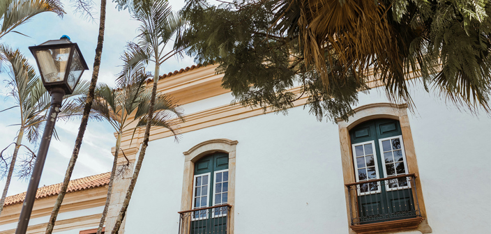 Exterior facing wall of Spanish house showing windows and branches of trees
