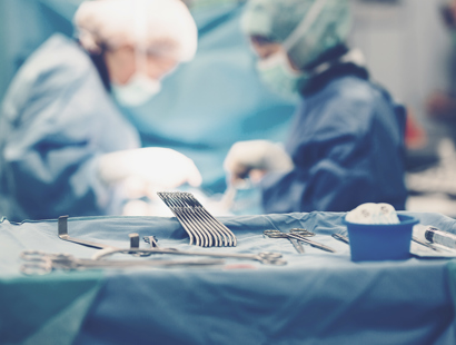 Surgeons in operating room, with medical equipment in the foreground. Surgical claims for children