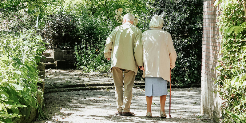 Elderly couple walking hand-in-hand in a leafy footpath. Lessons on immigration compliance for businesses–sponsor licence revoked for care home group