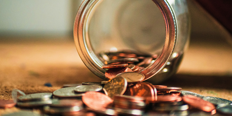 A glass jar pouring coins onto the table. The Autumn Statement and your money—Financial Times