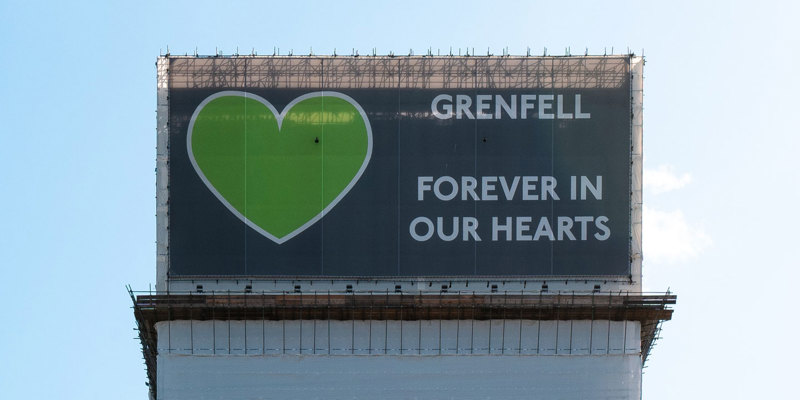 Grenfell Tower Inquiry Phase 2 Report findings – Legal support from Russell-Cooke for Grenfell victims. Image of a banner covering the Grenfell Tower. The banner has a large green heart and the words "Grenfell, forever in our hearts".