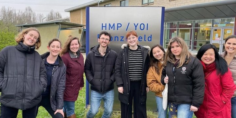 Group of volunteers in colourful clothing outside prison after delivering a singing workshop 