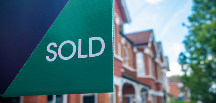 Russell-Cooke-Conveyancing fee information. Image of a for sale sign with a blurred background containing terraced houses.